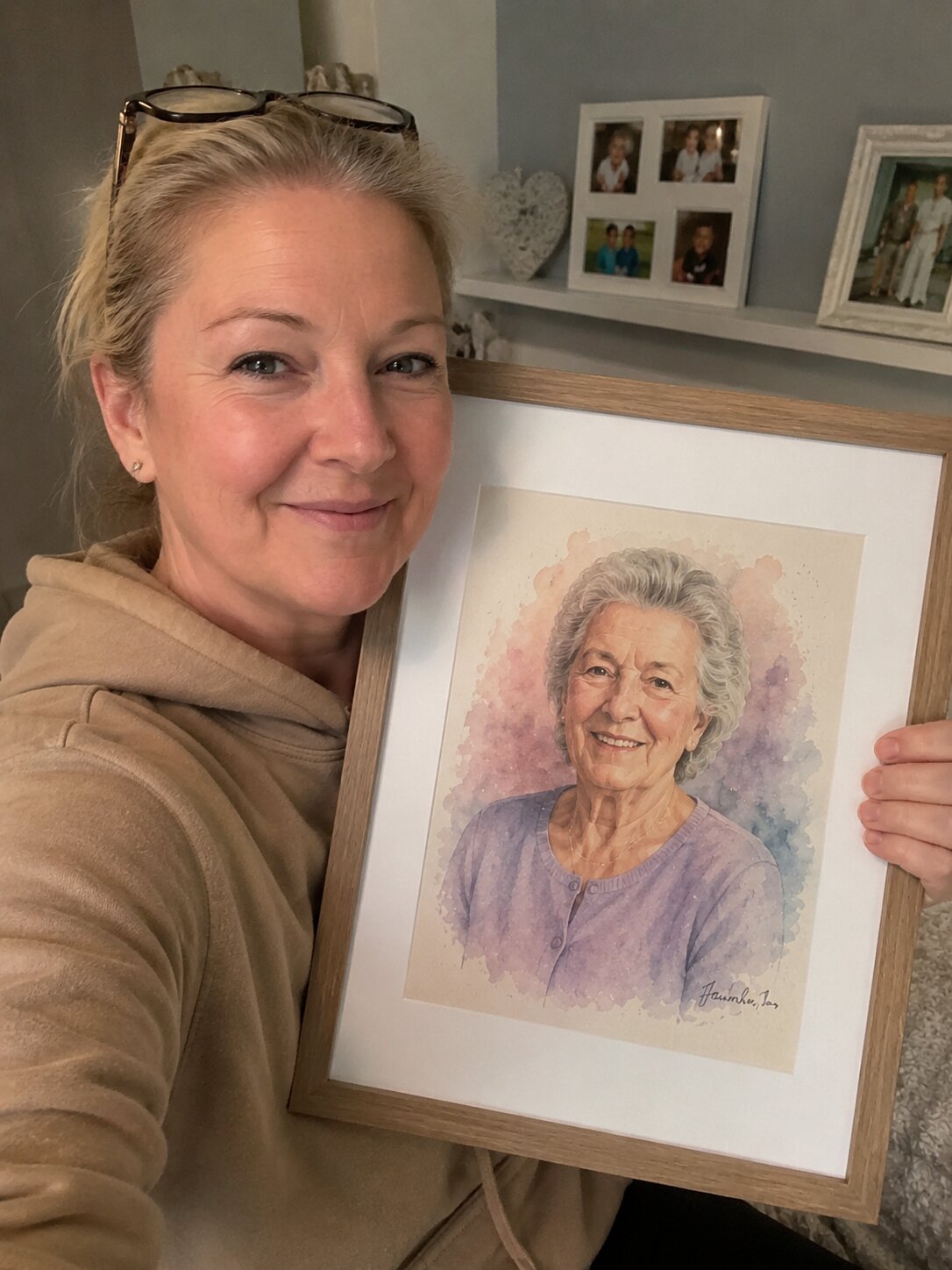 A woman from Manchester smiling next to a framed watercolor portrait of her late mother